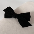 Close-up of black velvet bow hair clip with fine fabric texture on woven background - Black