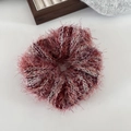 Close-up of fluffy mixed red and purple knit scrunchie texture and soft yarn fabric - Red