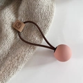 Detailed close-up of brown elastic hair tie with pink matte ball and bear leather label - Pink
