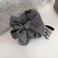 Close-up of grey herringbone fabric scrunchie with brand tag on white surface - Premium Gray