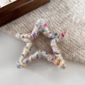 Dettaglio di un fermaglio per capelli a forma di stella avvolto in filato di lana colorato - Bianco AB