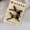 Close-up of brown suede bow hair clips with golden heart accents on packaging - Duckbill Hair Clips / Light Coffee