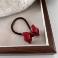 Detalle del lazo de resina rojo brillante en una goma para el pelo elástica marrón - Lazo