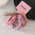 Dettaglio di quattro elastici per capelli arricciati in colori Morandi e tessuto elasticizzato - Rosa