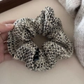 Detail of tweed scrunchie featuring woven texture and decorative black brand label - Grey-Beige