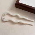 Detail view of pearlescent wave acetate hair fork with crystal inlay and gold lettering - Mermaid White