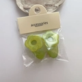 Close-up of two green floral resin hair clips on a card packaging with accessories text - Green