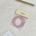 Detailansicht der rosa transparenten Spiral-Haargummis in einer Verpackung - Rosa