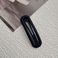 Close-up of matte black metal oval hollow hair clip on a textured white surface - 4# Black