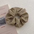 Detail shot of khaki bubble texture scrunchie with soft fabric pleats and woven tag - Khaki