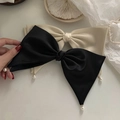 Detalle de pinza para el pelo con lazo de satén, colgante de perla blanca y cadena de oro - Negro