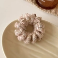 Detalle de coletero de lana rosa tejida con hilos dorados en un plato de cerámica - Rosa