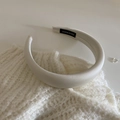 Macro detail of white satin sponge headband with black handmade label on knit fabric - White