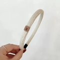 Close-up of cream knit headband with a brown leather rabbit patch and black comfort tips - Beige