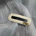 Makroaufnahme der cremefarbenen gesteppten Leder-Haarspange mit goldenem Metall-Logo - Weiß
