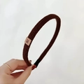 Detail of dark brown knitted headband featuring a small leather patch with a rabbit icon - Brown