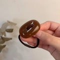 Close-up of a minimalist amber resin hair tie with a durable dark brown elastic band - Caramel color