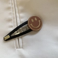 Detalle de pinza para pelo en tela negra con carita sonriente dorada y placa artesanal - Pinza para el cabello / Clip BB Smiley Café