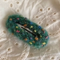 Detail der handgewebten grünen Garn-Haarspange mit bunten Regenbogen-Pompons auf Spitze - Grün