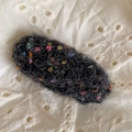 Gros plan d'une pince à cheveux tricotée noire avec des pois colorés et une texture douce - Noir