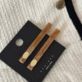 Détail de deux pinces à cheveux en acétate ambré avec des disques dorés sur tissu tweed - Café Clair