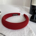 Detail of a dark red padded headband with textured fabric and a handmade label - Retro Copper