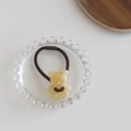 Detailed shot of a creamy translucent resin bear charm on a brown elastic hair tie - Yellow