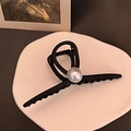 Detalle de pinza de pelo negra mate con perla grande sobre bandeja decorativa - Negro
