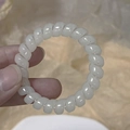 Close-up of translucent white spiral telephone wire hair tie held by hand for scale - Off-white