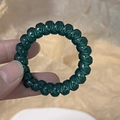 Detailed close-up of a dark green spiral hair tie with a jelly-like transparent finish - Lake Blue