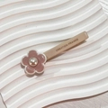 Detail of pink floral hair clip with pearl center and Creation France text on beige clip - Pink