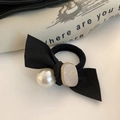 Dettaglio dell'elastico per capelli in raso nero con perla bianca e decoro in metallo - Beige