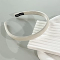 Detail showing the white fabric headband with a black hand-made woven label on textured surface - Off White
