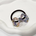 Dettaglio dell'elastico per capelli con fiocco in resina marmorizzata su vassoio - Viola fantasma