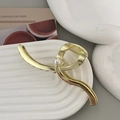 Elegante pinza per capelli in metallo dorato con una grande perla su un piatto decorativo - Oro