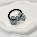 Close-up of blue marble pattern acetate bow hair tie on a white decorative tray - White Blue
