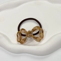 Detail of tortoiseshell pattern bow hair tie on a white minimalist display tray - Milk Coffee