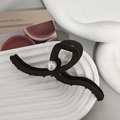 Detail einer großen matt schwarzen Haarklammer mit Perle auf einem weißen Tablett - Matt Dunkelkaffee