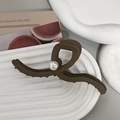 Detail einer matt dunklen Haarklammer mit Perle auf einem weiß strukturierten Keramiktablett - Mattes Khaki