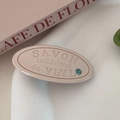 Détail de la pince à cheveux ovale avec lettres en relief et strass bleu brillant - Blanc Cassé