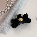 Detalle de una pinza para el pelo con lazo de satén negro y un botón de metal dorado grabado - Negro