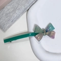 Gros plan d'une pince à cheveux avec nœud en résine dégradé et poignée vert émeraude - Couleur Aurore