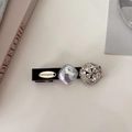 Close-up of pearl hair clip with purple crystal and gold-tone brand plate detail - Black Round Zirconia