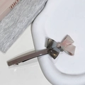 Gros plan détaillé d'une barrette à nœud en acétate tricolore sur un plateau blanc élégant - Gris Multicolore
