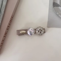 Detalle de pinza de pelo en satén gris con adornos de cristal y emblema dorado elegante - Piedra Redonda Champaña