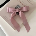 Detalle de un lazo de raso rosa para el pelo con cintas largas sobre una revista - Rosa