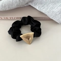 Dettaglio di un elastico in raso nero con fibbia in metallo triangolare oro spazzolato - Stile Triangolo / Nero