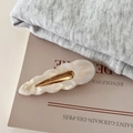 Gros plan sur la barrette à cheveux ondulée blanc crème avec finition nacrée et base dorée - Couleur Sirène