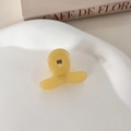 Detalle de una mini pinza para el pelo de acetato amarillo con logo dorado y muelle metálico - Amarillo Lácteo