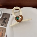 Detail van de crèmekleurige hart-haarklem met smaragdgroene en traan-strass-steentjes - Off-wit